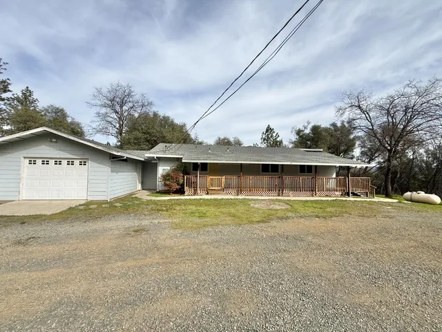 a view of a house with a yard and large tree