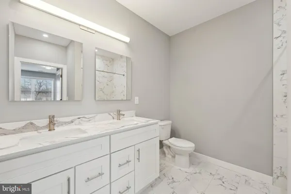 a bathroom with a double vanity sink toilet and a mirror
