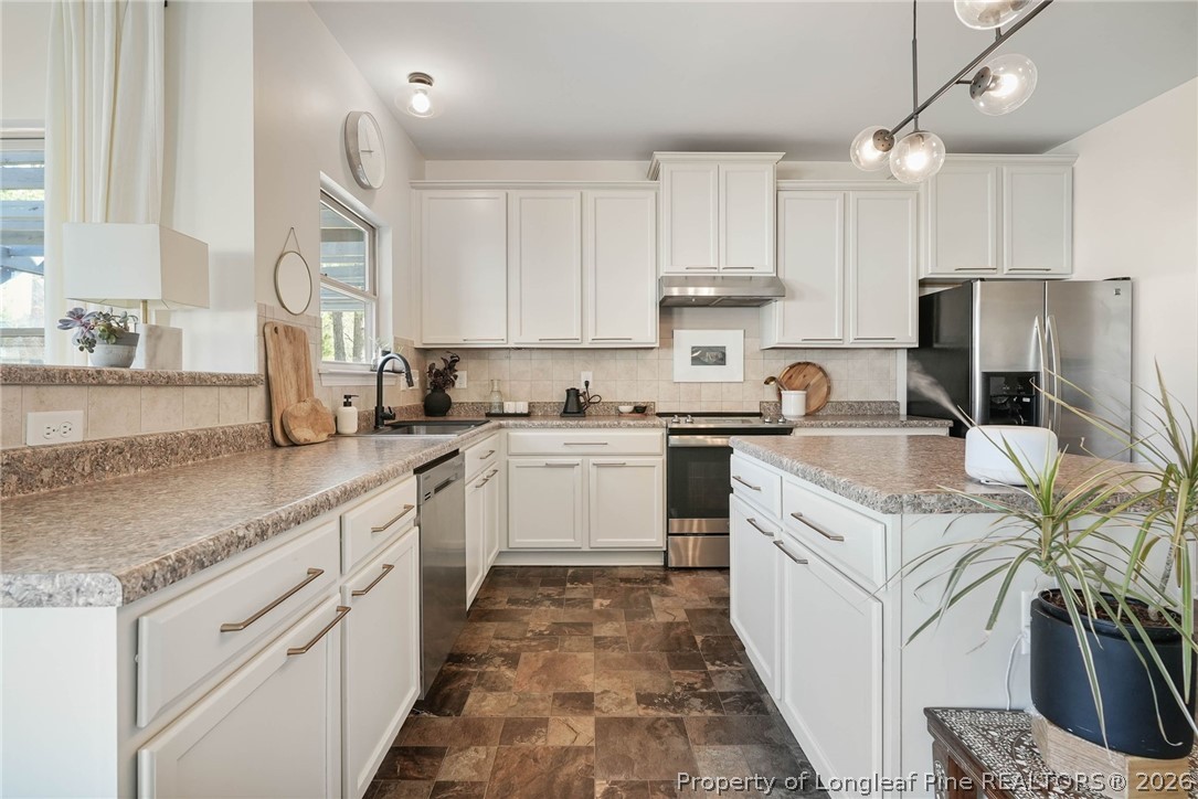 1219 Coachman Way Sanford, NC 27332 - Photo 14 of 46 a kitchen with white cabinets sink and stainless steel appliances