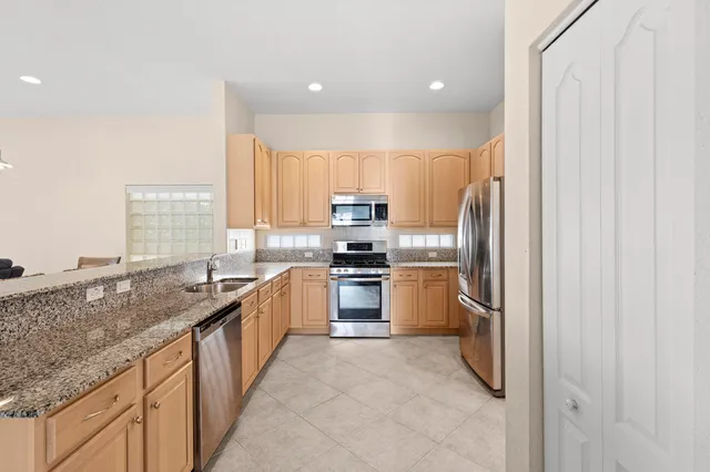 a kitchen with granite countertop a sink stainless steel appliances and white cabinets
