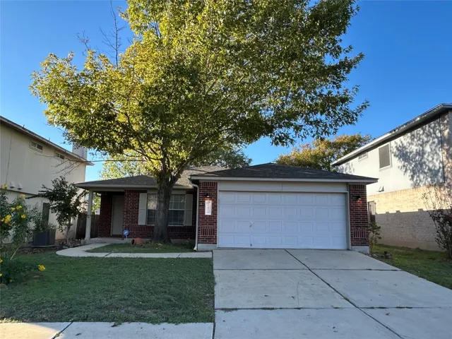 a front view of a house with a garden and trees