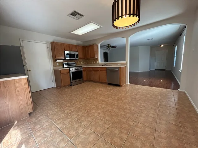 a large kitchen with a large counter top stainless steel appliances and cabinets