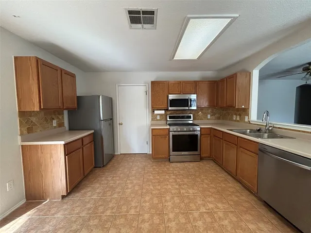 a large kitchen with cabinets a counter top space stainless steel appliances and cabinets