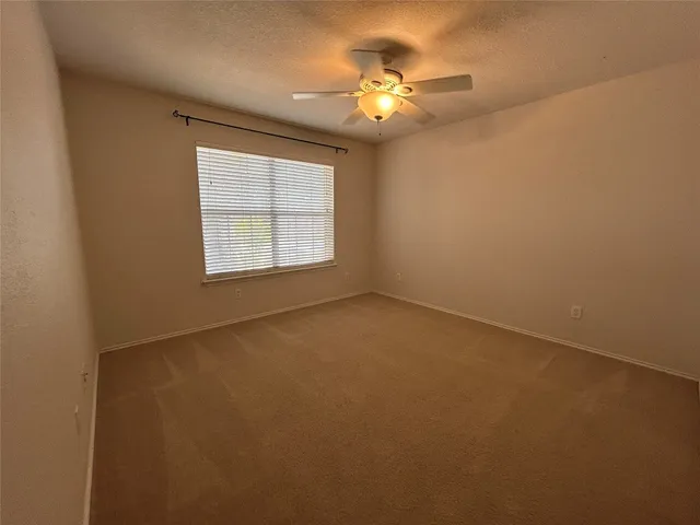 an empty room with windows and chandelier fan