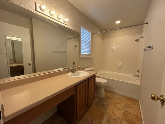 a bathroom with a granite countertop sink a toilet and shower