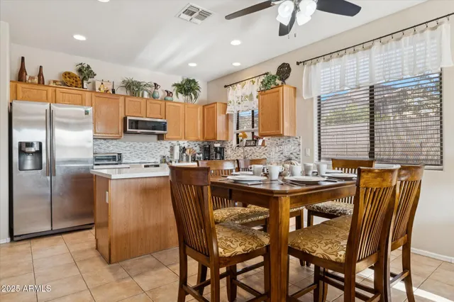 a kitchen with stainless steel appliances kitchen island granite countertop a table chairs and a refrigerator