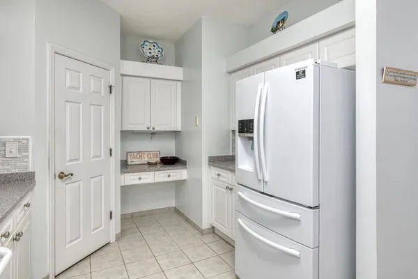 a kitchen with white cabinets and refrigerator