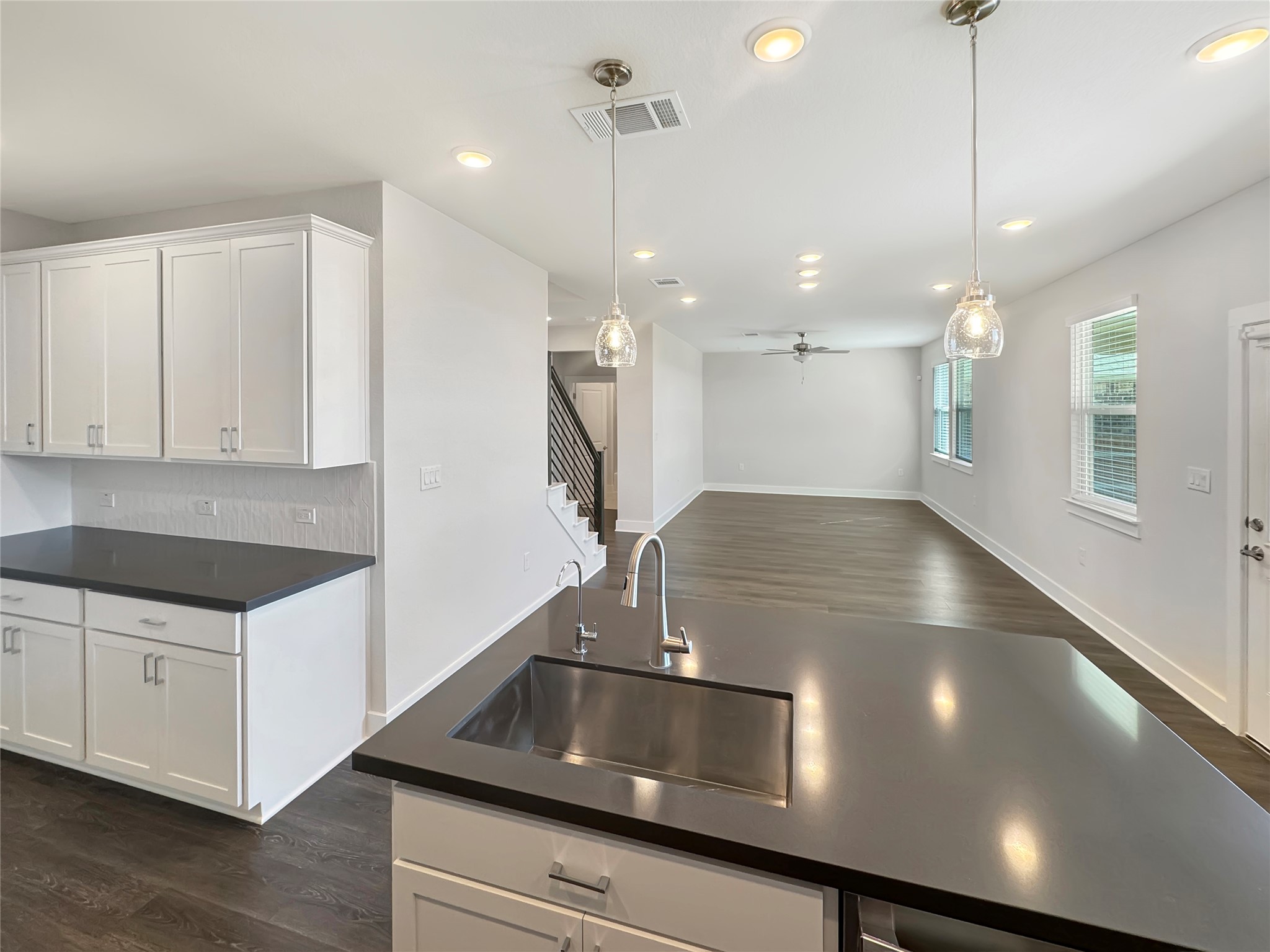 1704 Carvin Way Pflugerville, TX 78660 - Photo 30 of 30 Kitchen featuring dark wood-style flooring, open floor plan, white cabinets, a ceiling fan, and pendant lighting