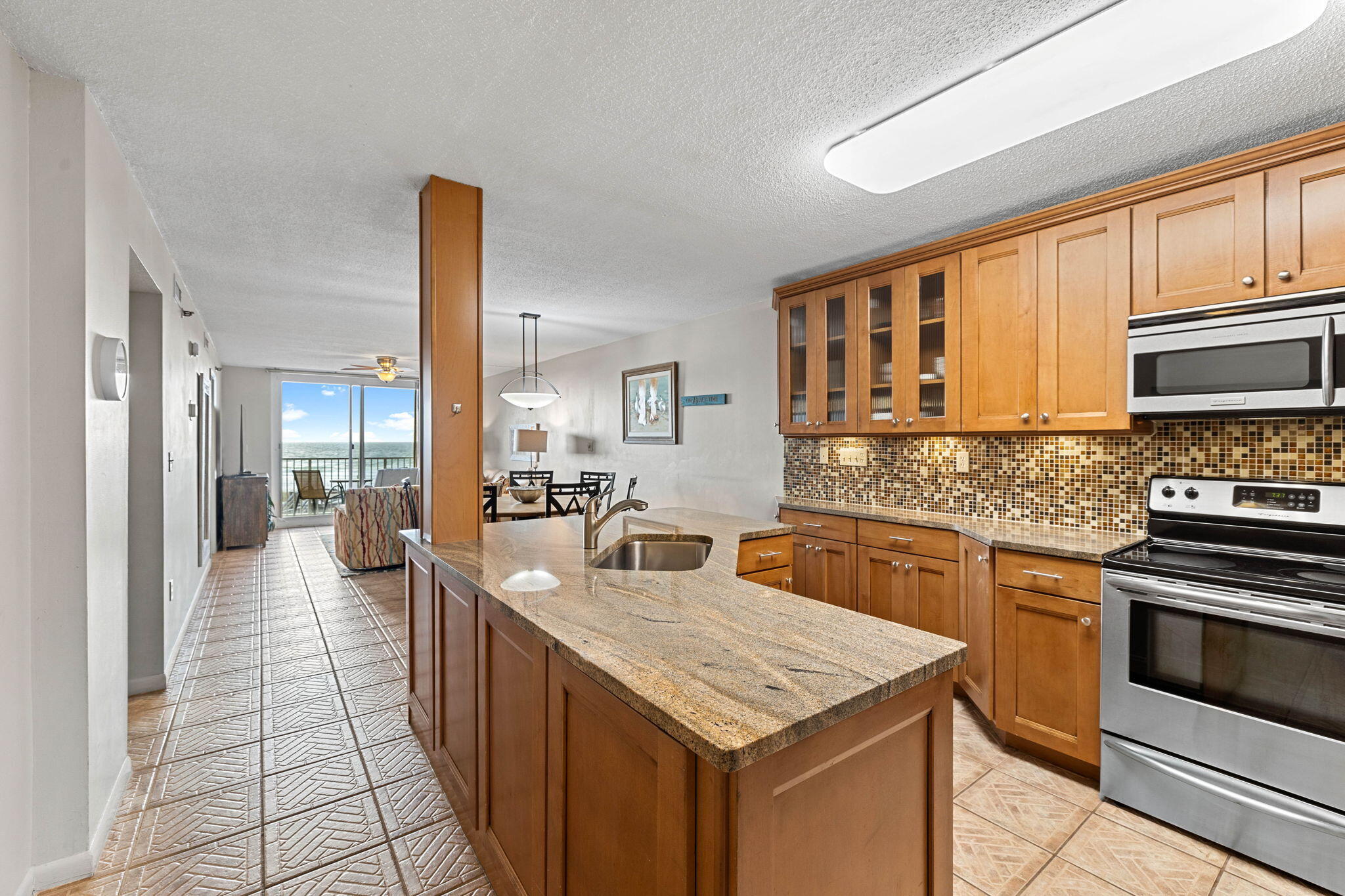600 Gulf Shore Drive, Unit 304 Destin, FL 32541 - Photo 3 of 38 a kitchen with stainless steel appliances granite countertop a stove top oven a sink dishwasher a dining table and chairs with wooden floor