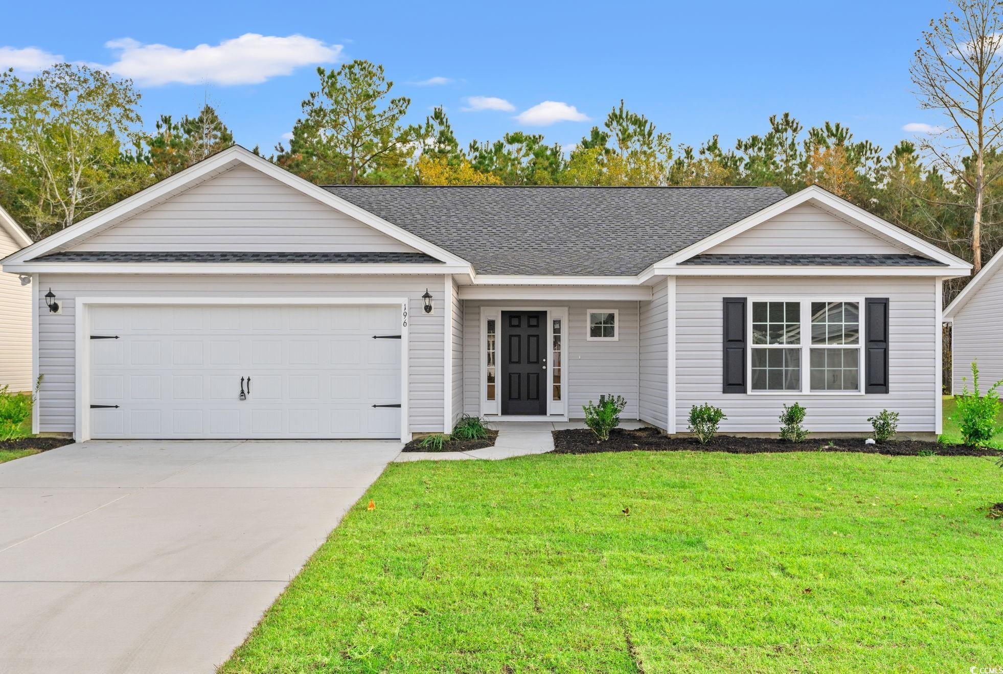 Ranch-style house featuring a shingled roof, a front yard, driveway, and a garage