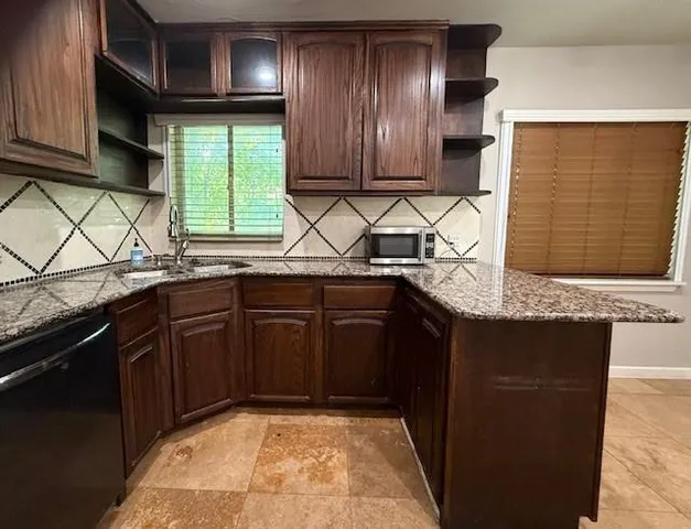a kitchen with stainless steel appliances granite countertop wooden cabinets a sink and a dishwasher