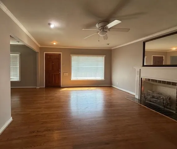 an empty room with wooden floor fireplace and windows