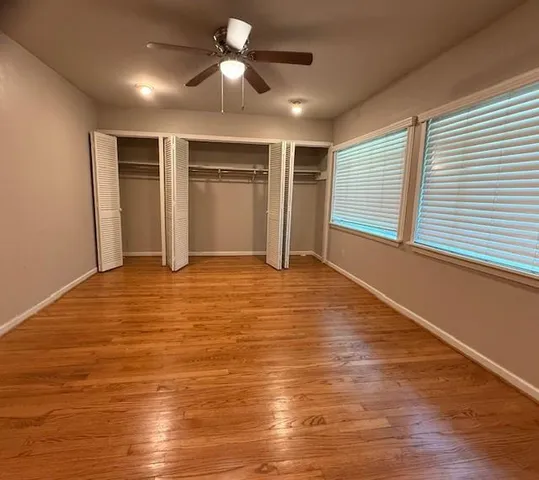 a view of an empty room with window and wooden floor