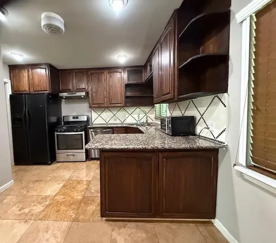 a kitchen with stainless steel appliances granite countertop a stove a refrigerator and a sink