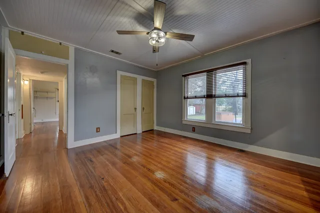 a view of an empty room with wooden floor and a window