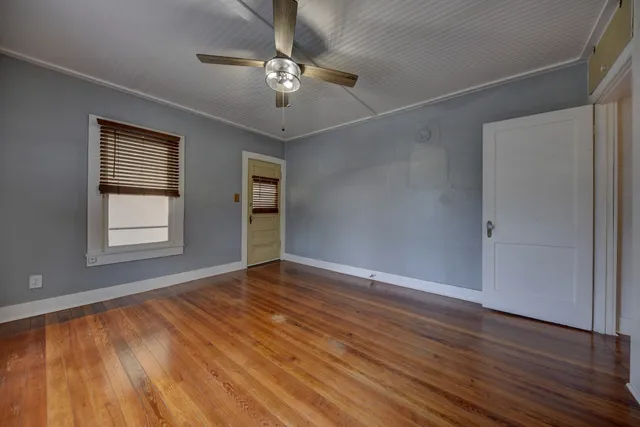 an empty room with wooden floor chandelier and windows
