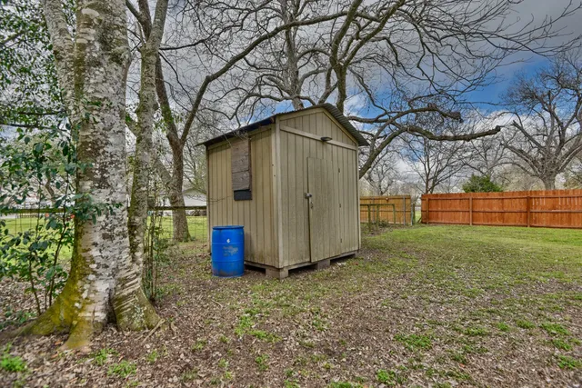 a small barn with a big yard and large trees