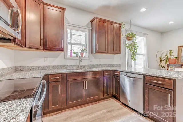 a kitchen with stainless steel appliances granite countertop a sink stove and cabinets