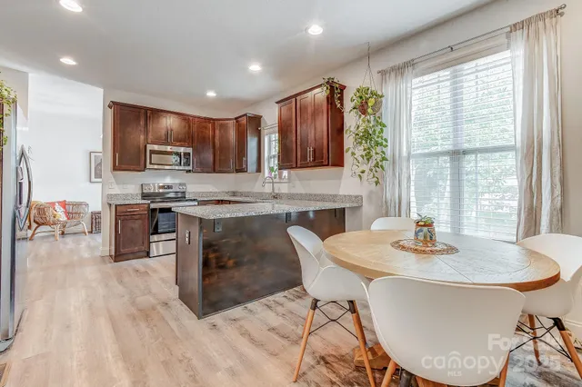 a kitchen with kitchen island granite countertop a stove a sink a dining table and chairs