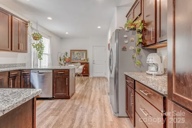 a kitchen with stainless steel appliances granite countertop a sink a stove and a wooden floors
