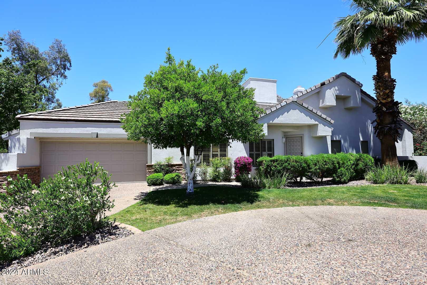 a front view of a house with a garden and trees