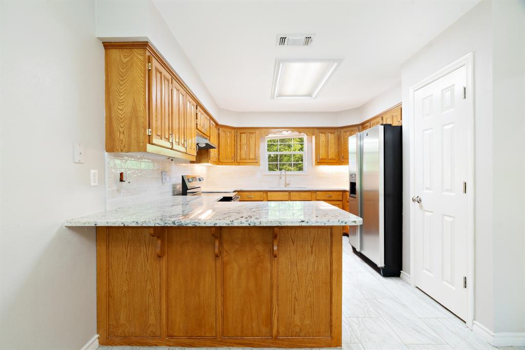 239 Deer Valley Drive Powderly, TX 75473 - Photo 7 of 18 a kitchen with granite countertop wooden cabinets and a window