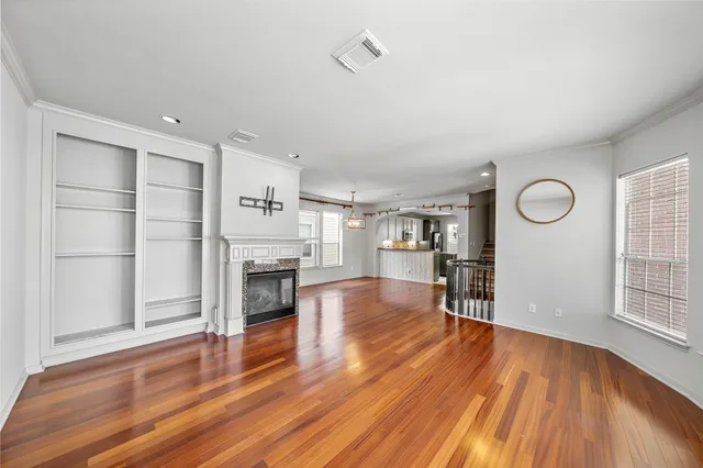 an empty room with wooden floor fireplace and windows