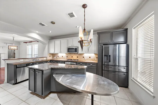 a kitchen with stainless steel appliances granite countertop a sink a stove a refrigerator and island