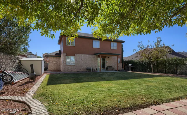 a view of a yard in front of a house with plants and large tree