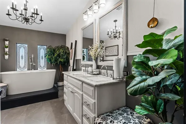 a bathroom with a sink a mirror and a potted plant