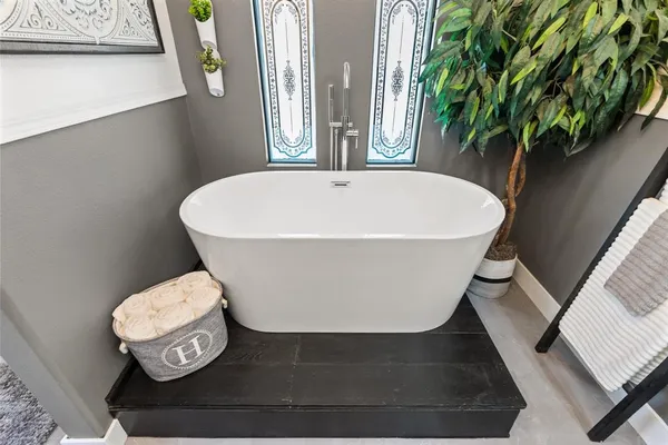 a white bath tub sitting in a bathroom next to a window