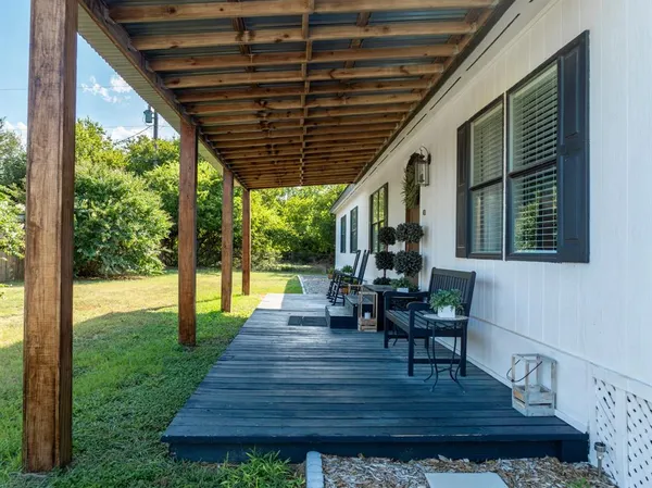 a view of a patio with table and chairs potted plants and floor to ceiling window
