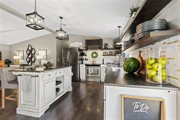 a kitchen with stainless steel appliances granite countertop a sink a stove and a wooden floor