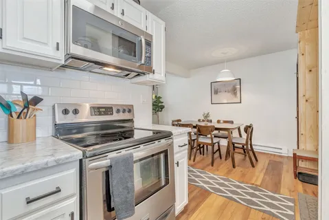 a kitchen with stainless steel appliances granite countertop a stove a microwave and a dining table with wooden floor