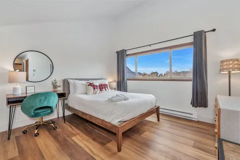 a bedroom with a bed and a lamp with wooden floor