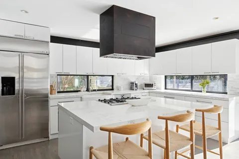 a kitchen with stainless steel appliances kitchen island granite countertop a kitchen island and chairs in it