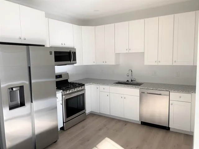 a kitchen with granite countertop white cabinets and stainless steel appliances