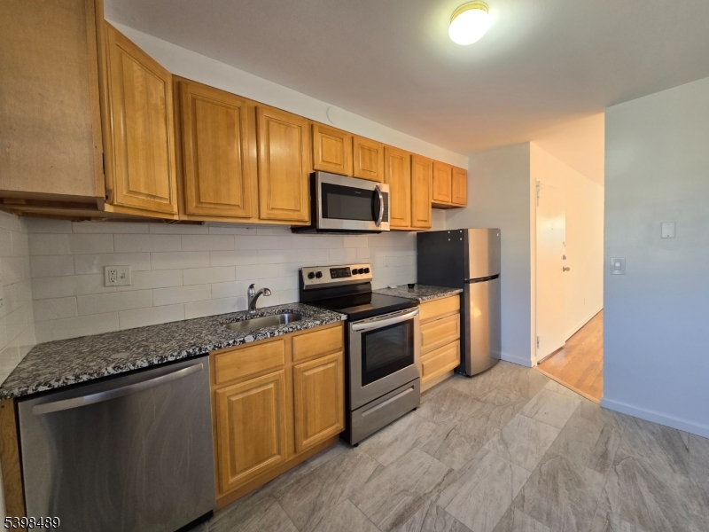 a kitchen with granite countertop wooden cabinets and a stove top oven