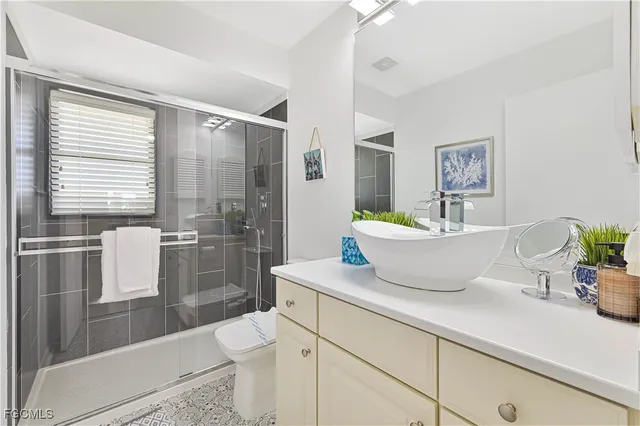 a bathroom with a granite countertop sink a toilet a shower and a mirror