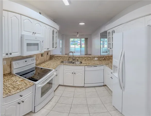 a kitchen with white cabinets and appliances