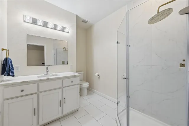 a bathroom with a granite countertop sink mirror and a toilet
