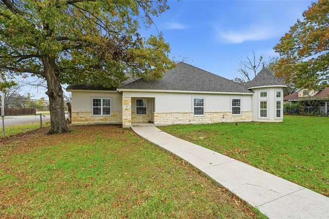 a view of house with a big yard and large trees