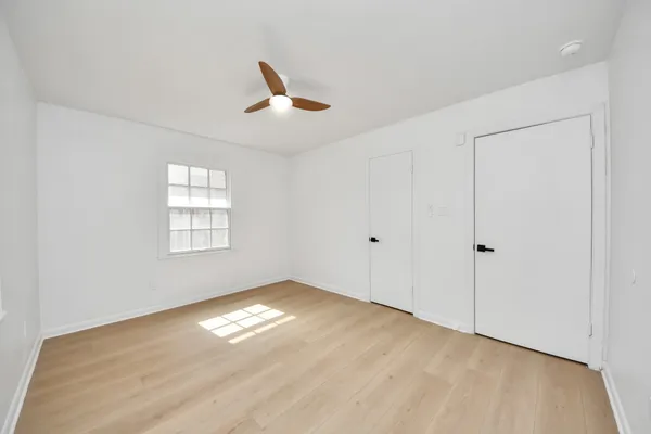 a view of empty room with wooden floor and fan