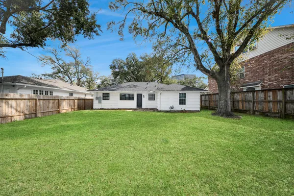 a view of a yard in front of a house with a large tree