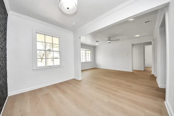 a view of an empty room with window and wooden floor