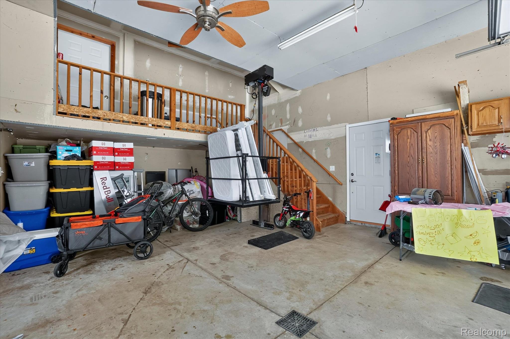 6524 Kelly Road Flushing, MI 48433 - Photo 36 of 47 Attached garage featuring concrete flooring, an upper-level storage area with wood railing, a ceiling fan, and a wood staircase