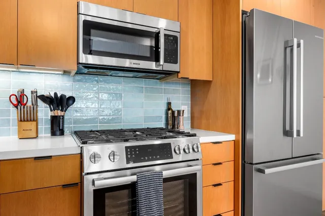 a kitchen with stainless steel appliances kitchen island granite countertop a stove a sink a dining table and chairs with wooden floor