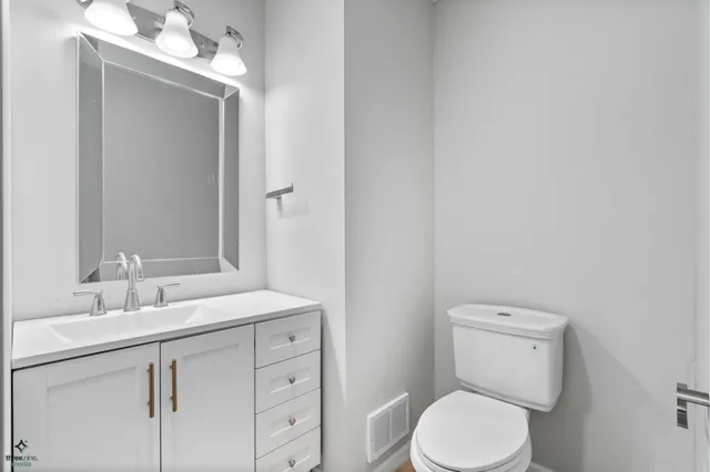 a bathroom with a toilet sink vanity and mirror