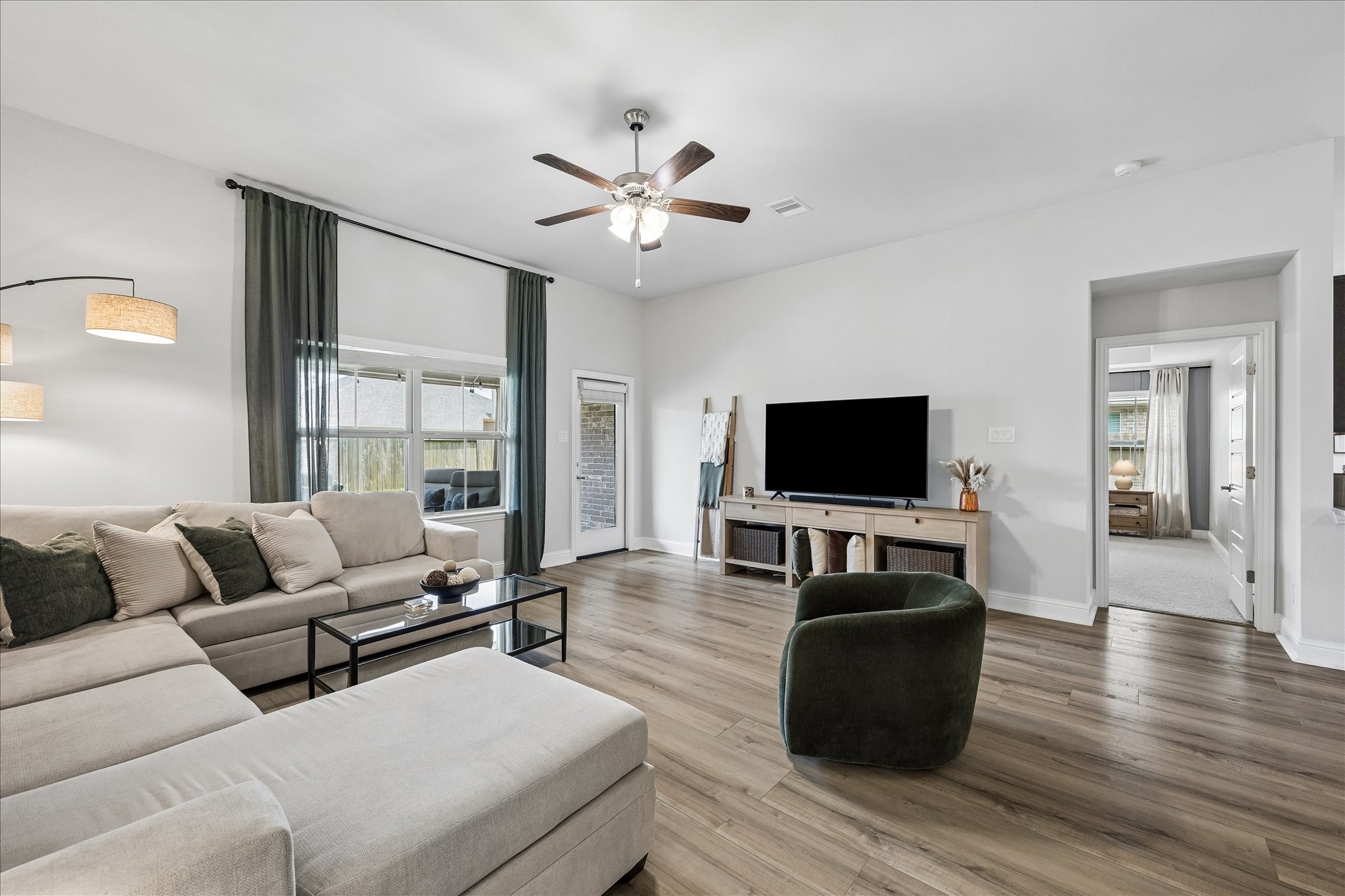 10227 Whitney Reach Drive Rosharon, TX 77583 - Photo 17 of 28 Bright living area with views of the backyard and a spacious paved patio. The primary bedroom is conveniently located on the right, with secondary bedrooms on the left for added privacy.