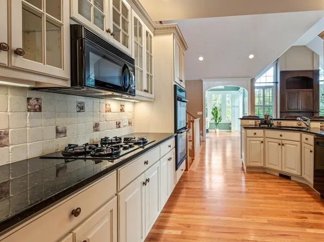 a kitchen with stainless steel appliances a sink stove and wooden floor